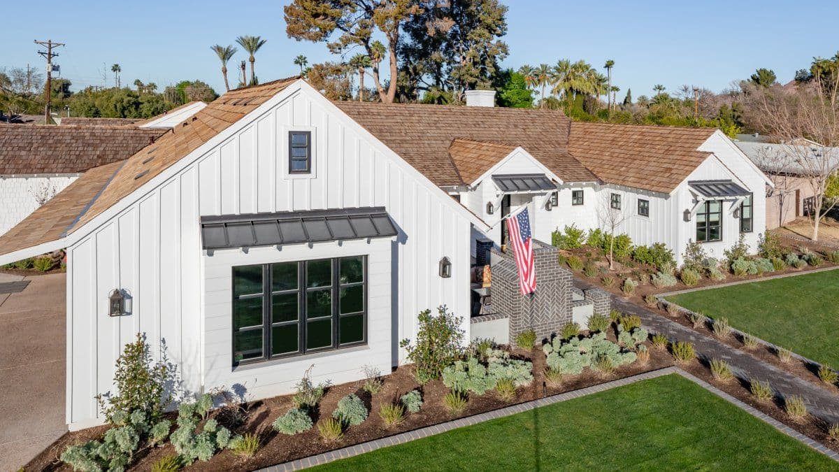 Modern white farmhouse with detached garage featuring black trim, metal awning, and landscaped front yard with drought-resistant plants and lawn - Westlake Royal