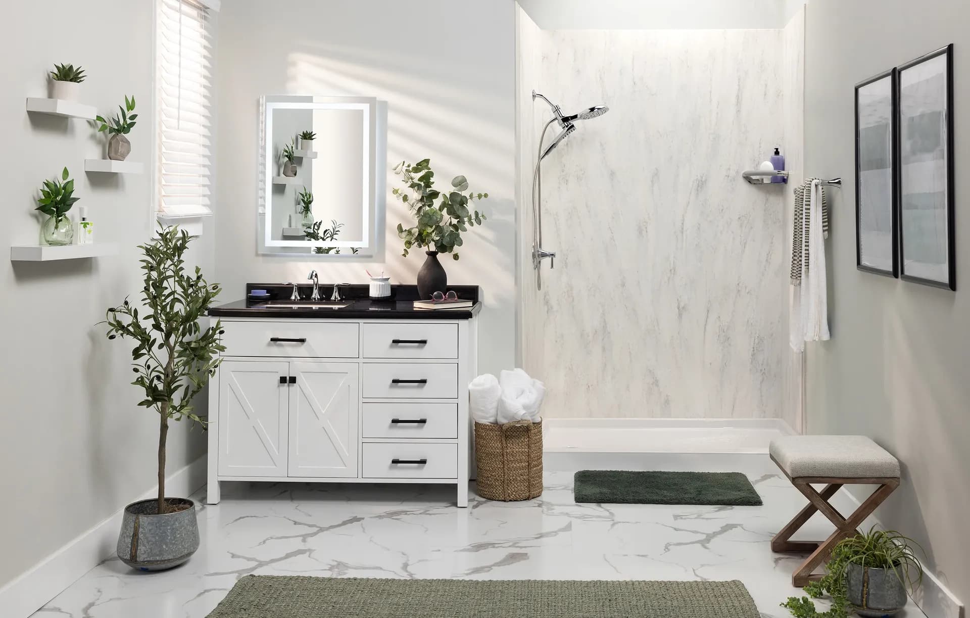 Modern bathroom with white cabinetry, marble countertops and shower walls, lighted mirror, potted plants on shelves, and walk-in shower with glass enclosure